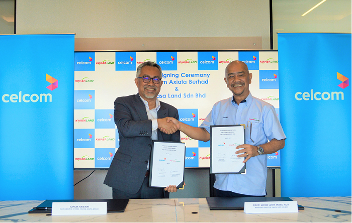 Celcom's Idham Nawawi (left) and Kwasa Land's Mohd Lotfy Mohd Noh, sign the agreement.