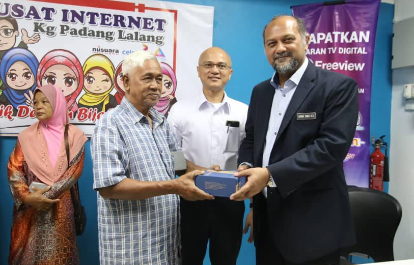 MCMC chairman Al-Ishsal Ishak (2nd right) and Communications and Multimedia minister Gobind Singh Deo (right) handing over set top boxes to Kampung Padang Lalang residents